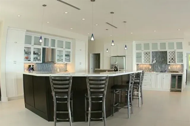 Modern white kitchen with a large black island and high stools