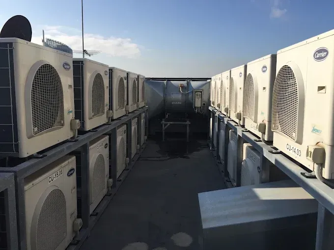 Rows of outdoor HVAC units on a rooftop under a clear blue sky