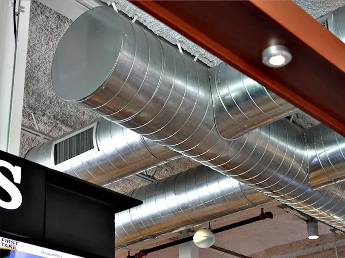 Silver HVAC ductwork and ceiling vent in an indoor industrial ceiling space