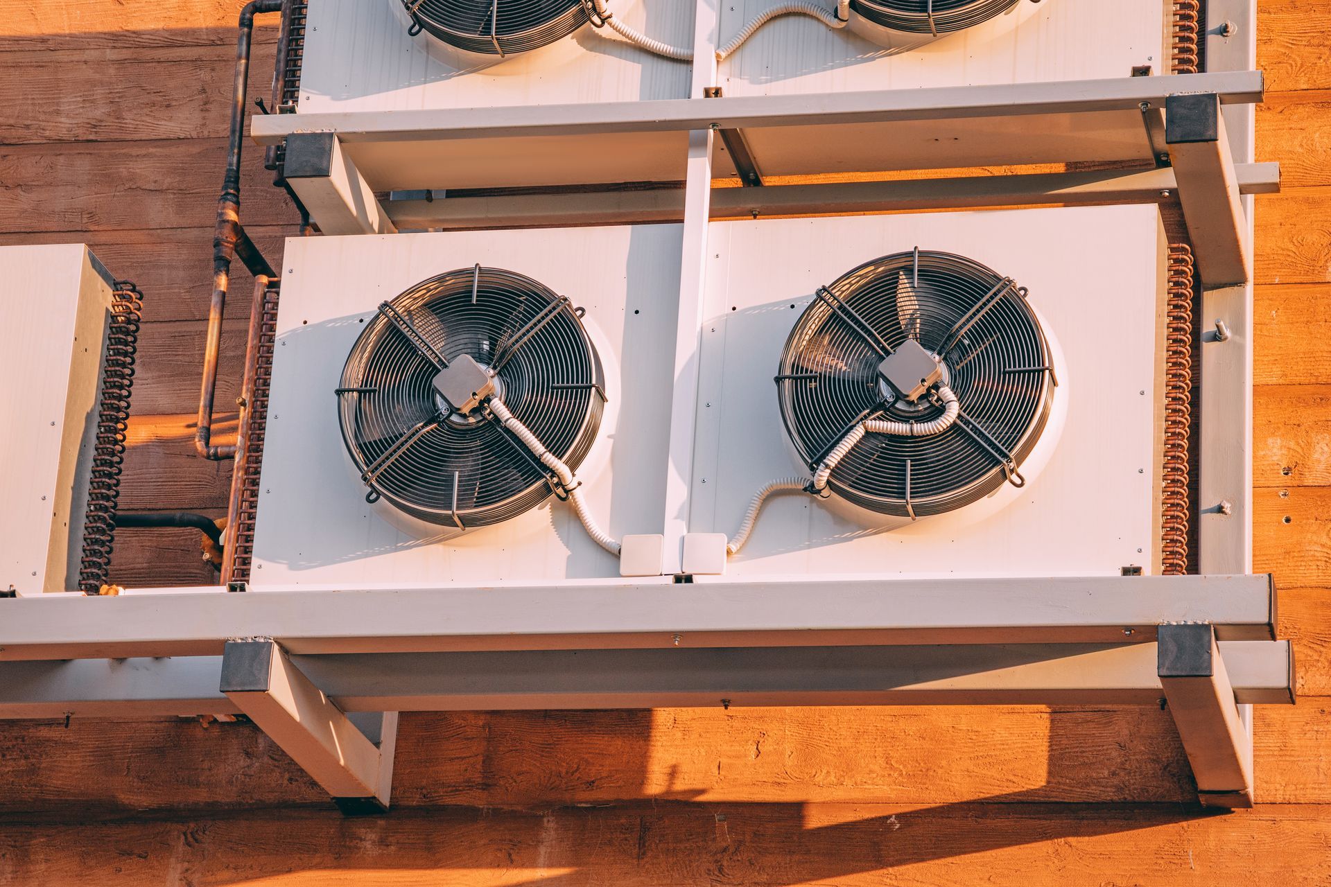 Outdoor wall-mounted cooling fans in white metal frames against a brick wall. Outdoor wall-mounted cooling fans in white metal frames against a brick wall.