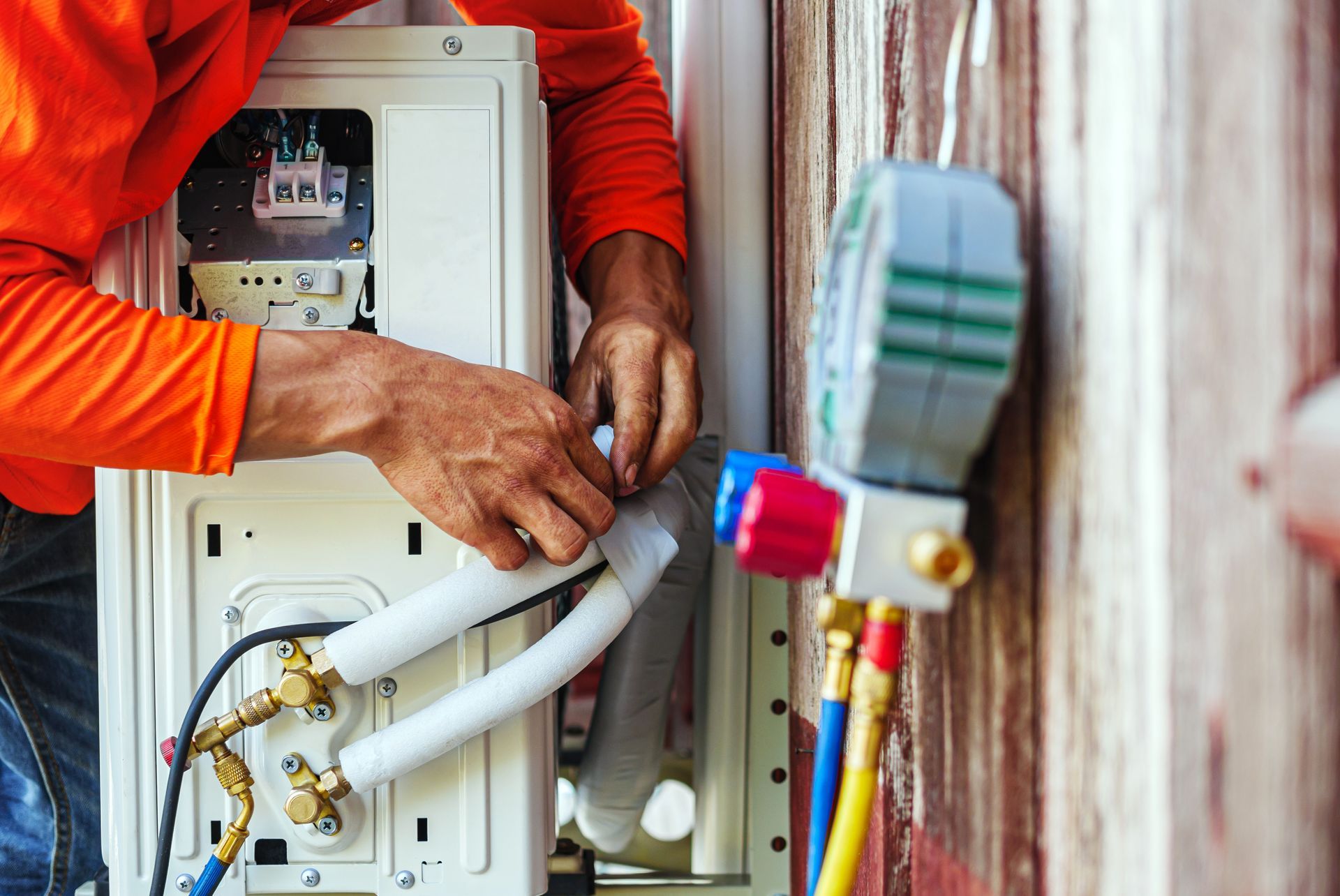 Technician servicing an outdoor HVAC unit with tools and white insulated tubing attached. Technician servicing an outdoor HVAC unit with tools and white insulated tubing attached.