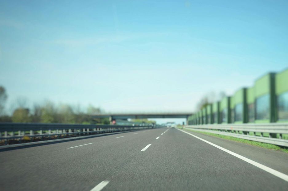 Empty highway stretches toward a distant bridge on a sunny day.