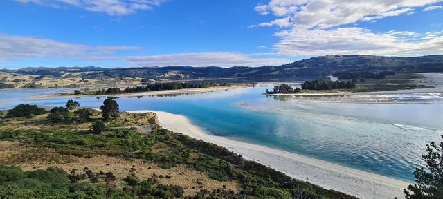 A turquoise river mouth winding to the coast between green hills