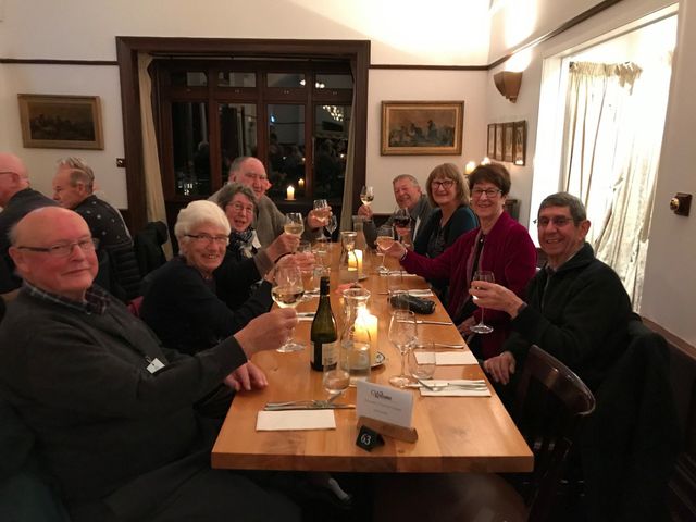 A group of guests raising their glasses at a long dinner table