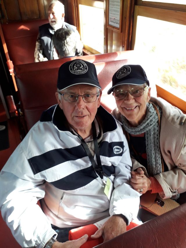 Two guests smiling in their seats in a train carriage