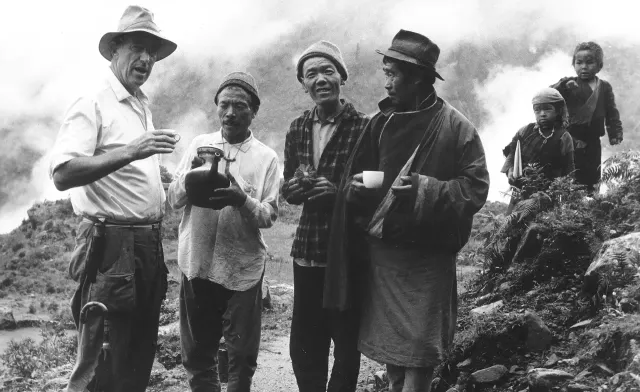 Black-and-white photograph of Sir Edmund Hillary talking with a group of Sherpa men