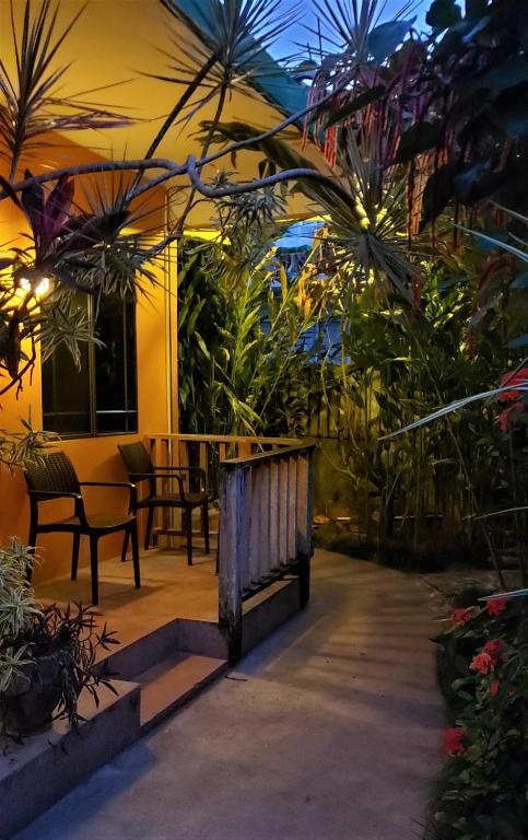 Outdoor seating area with chairs on a porch, surrounded by lush greenery and flowers, at dusk.