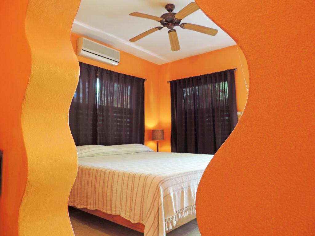 Bedroom with orange walls, brown curtains, a bed, and a ceiling fan.