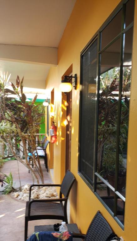 Yellow building exterior with black chairs, a window, and a light fixture.