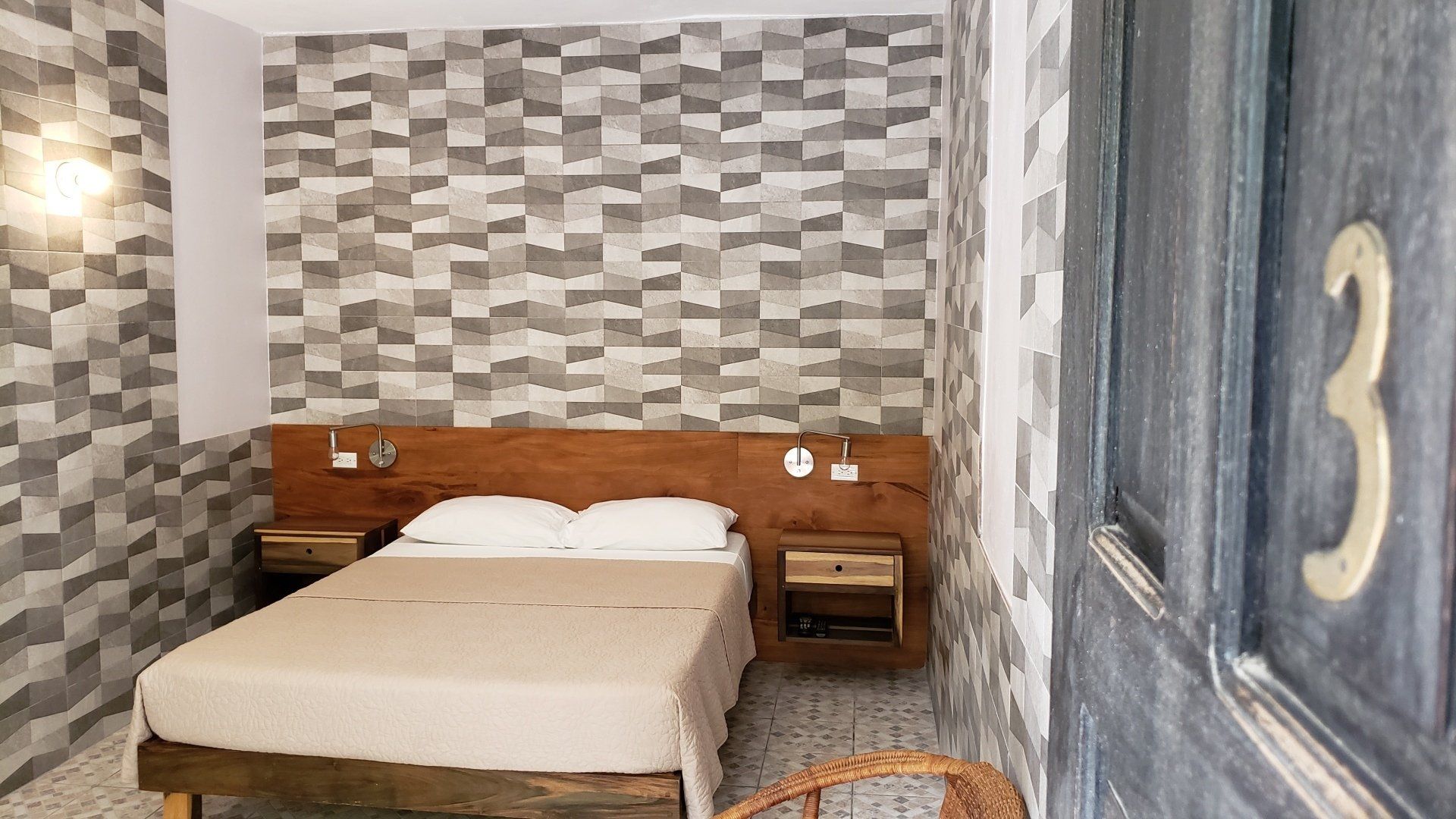 Bedroom with double bed, wooden headboard and nightstands, brick-patterned wall, and door with number 3.