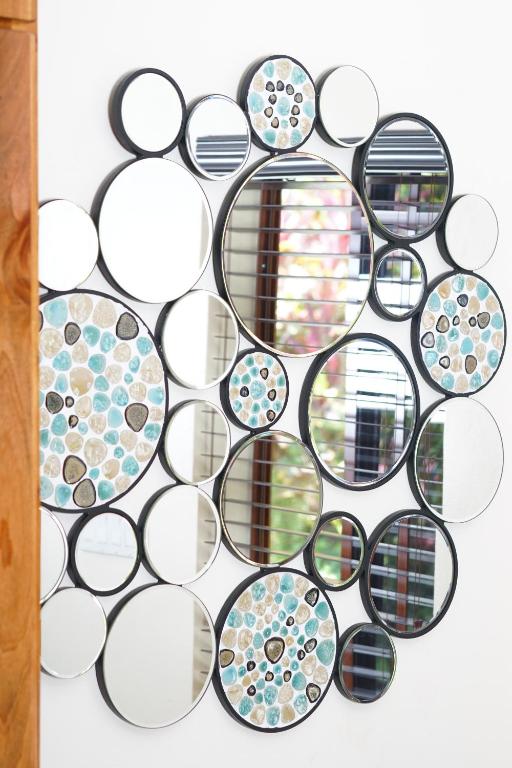 Circular mirrors of various sizes arranged in a cluster on a white wall. Some mirrors have a blue, mosaic-like design.