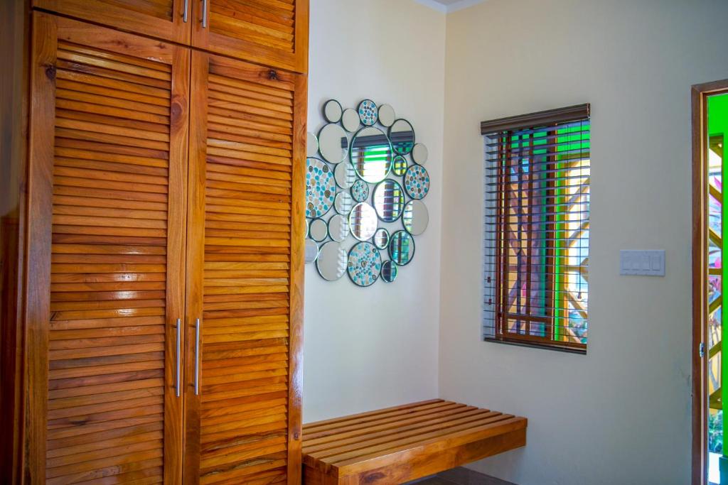 Wooden closet, bench, and mirror on a cream wall. A small window has green accents.