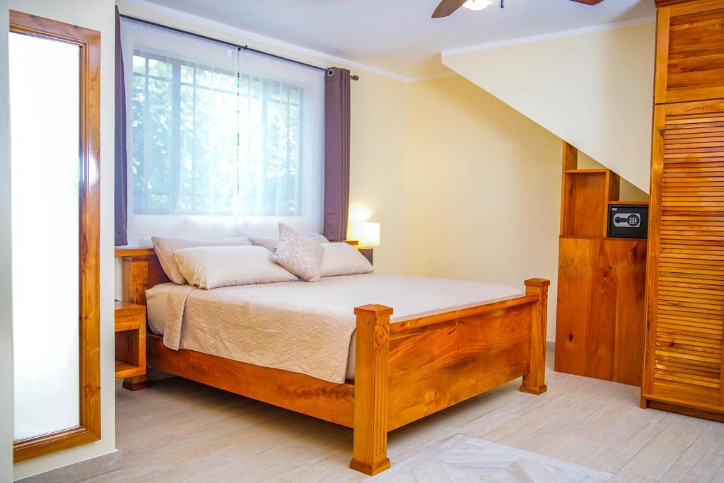 Bedroom with wooden bed, wardrobe, window, mirror, and light-colored walls.