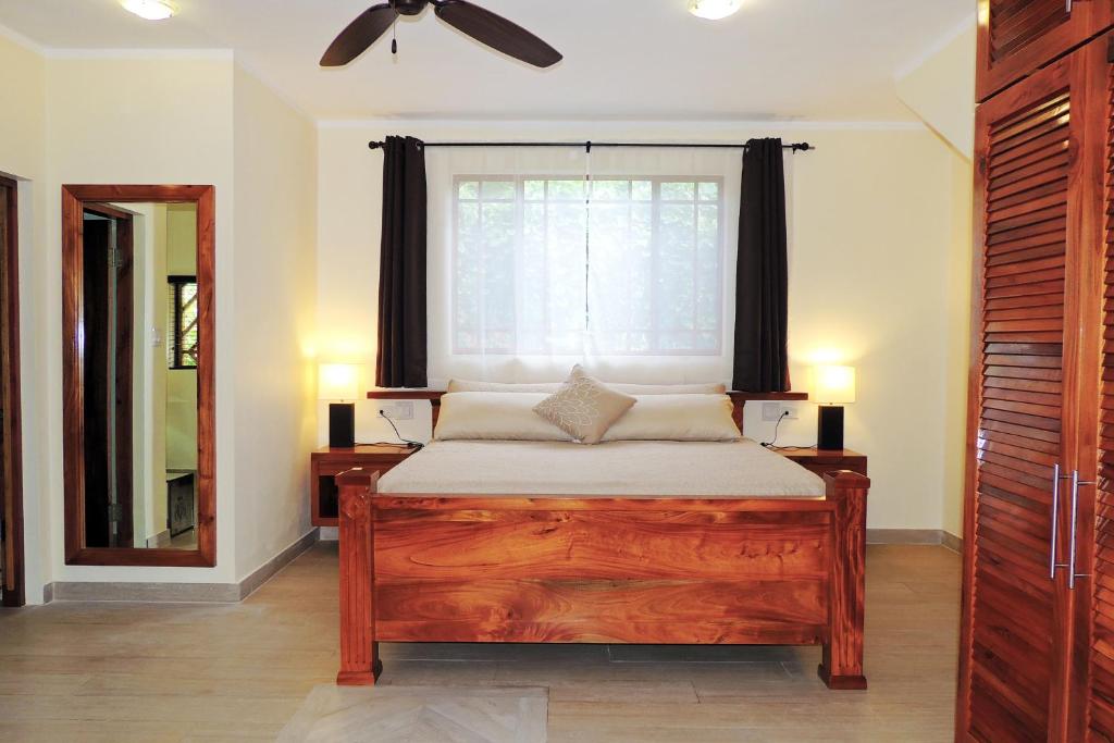 Bedroom with wooden bed, furniture, mirror, and window with dark curtains.