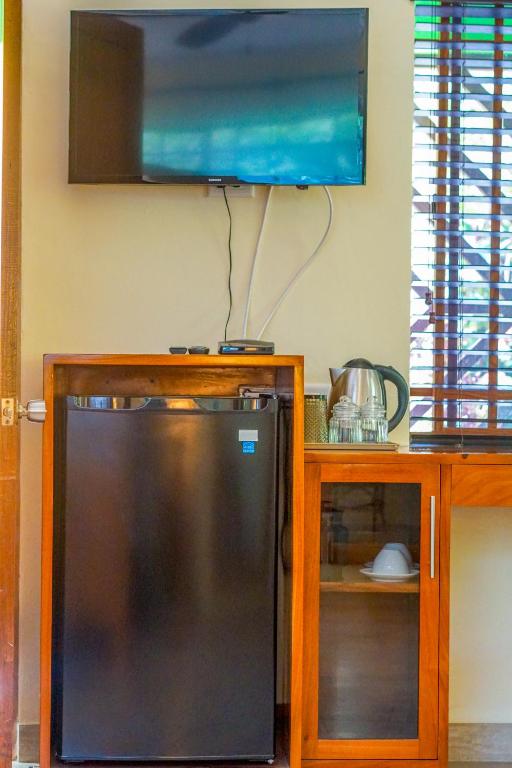 Mini-fridge and cabinet with TV mounted above it, near a window with blinds.