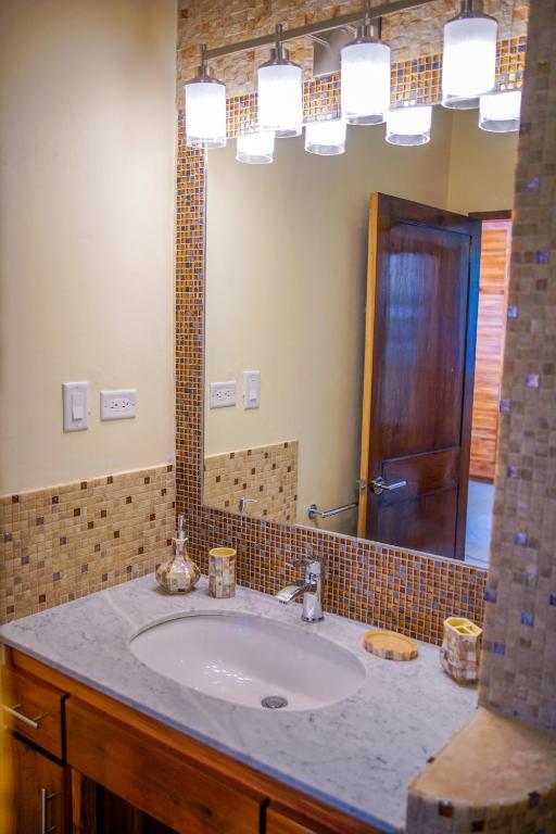 Bathroom with oval sink, marble countertop, wooden vanity, and mosaic tile accents.