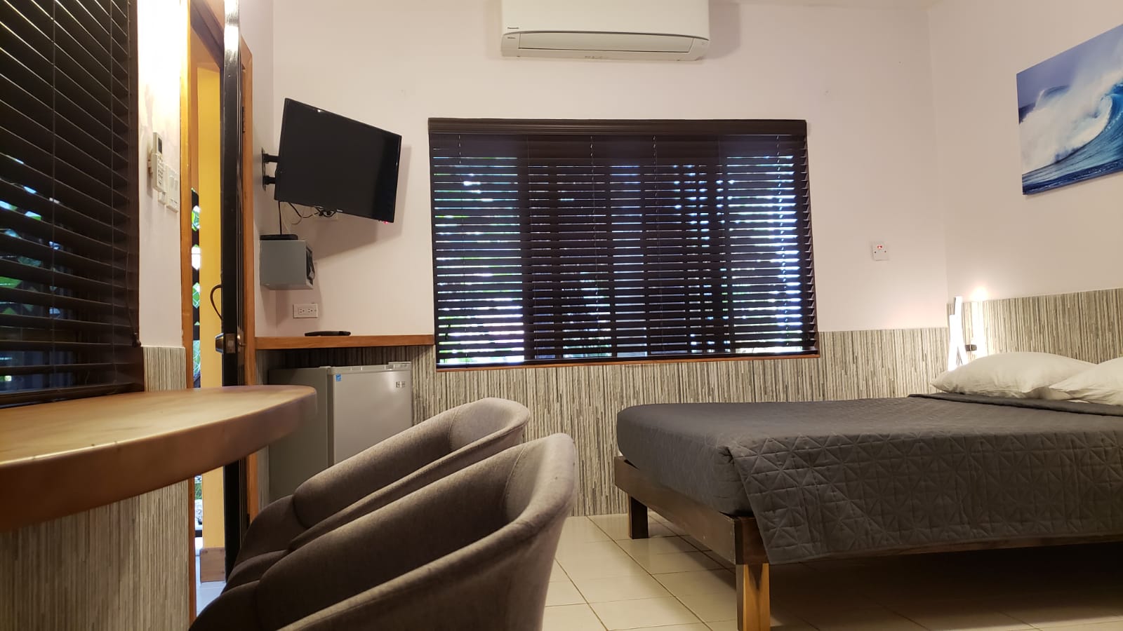 Bedroom with bed, chairs, TV, window, and air conditioner.