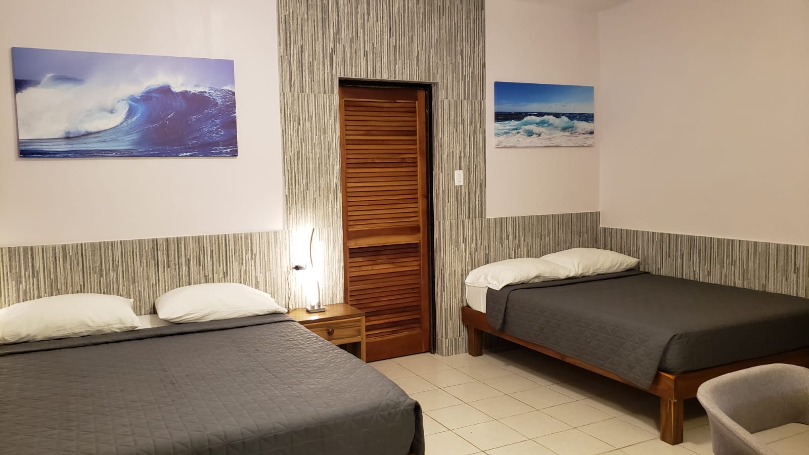 Bedroom with two beds, wave art, neutral color scheme, and a wooden door.
