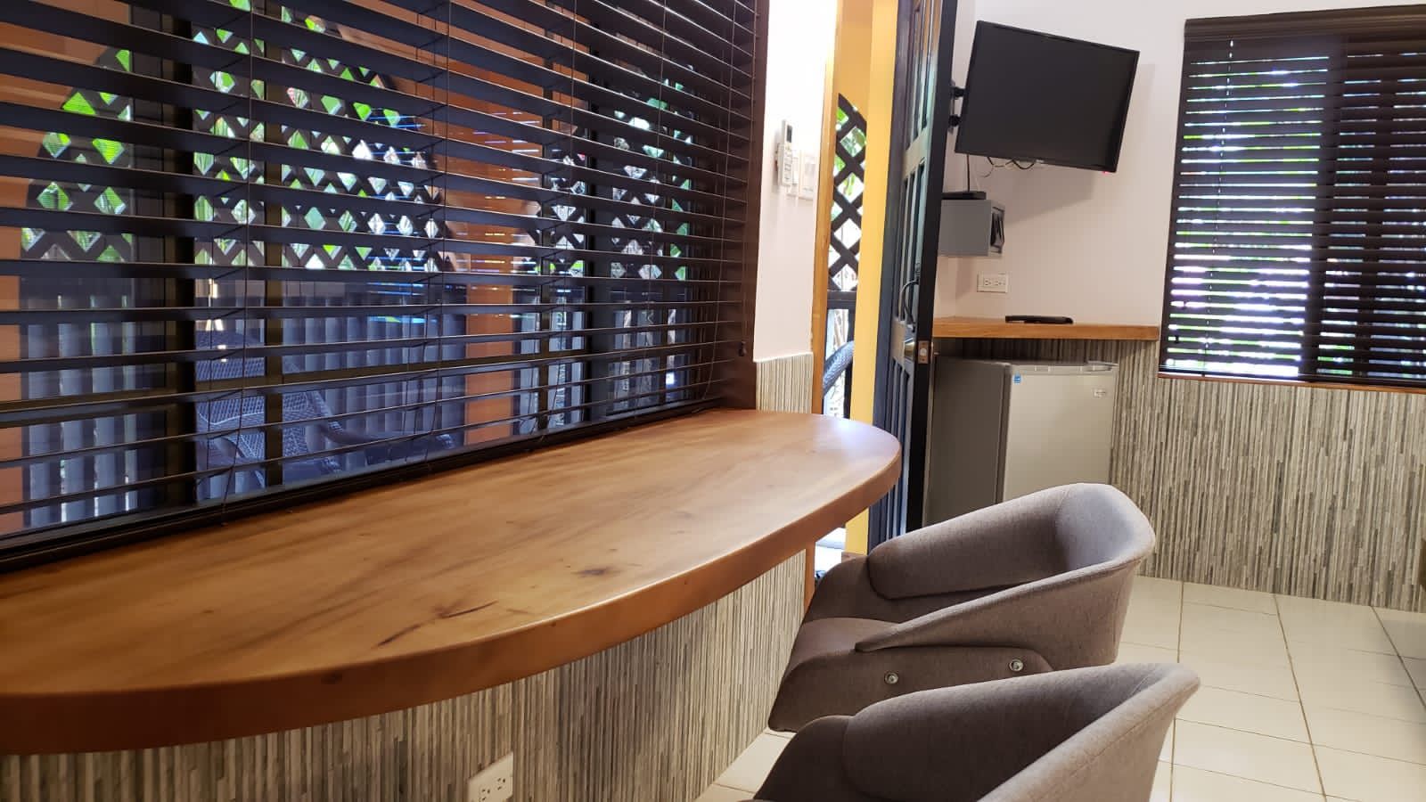 Interior with counter, chairs, blinds, small TV, and textured wall.