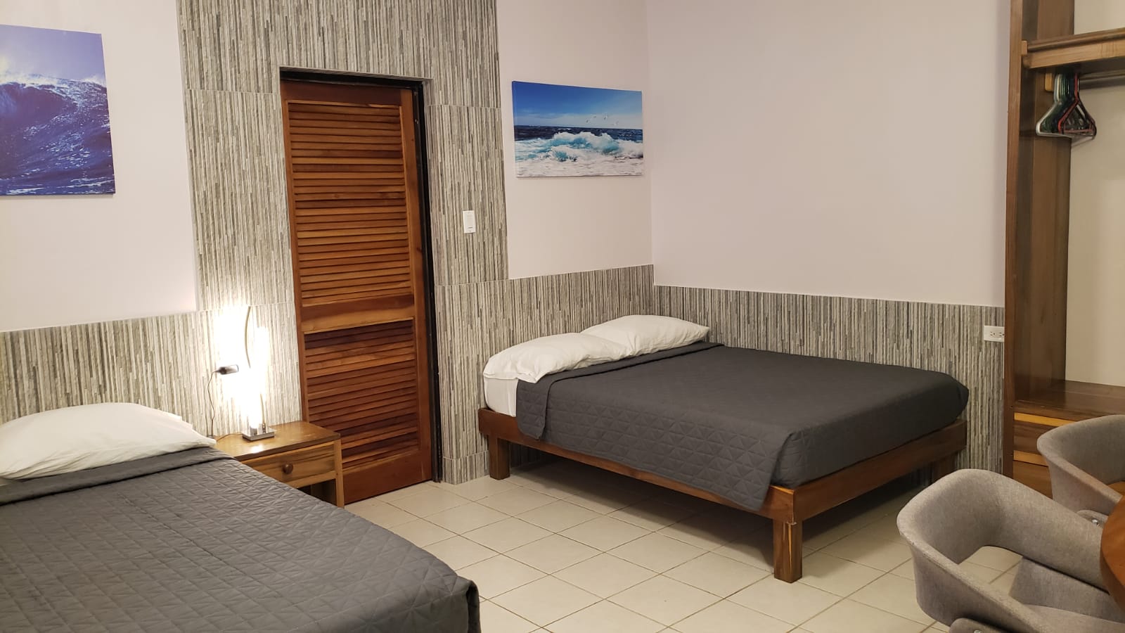 Bedroom with two beds, wooden door, artwork on walls, and neutral color scheme.