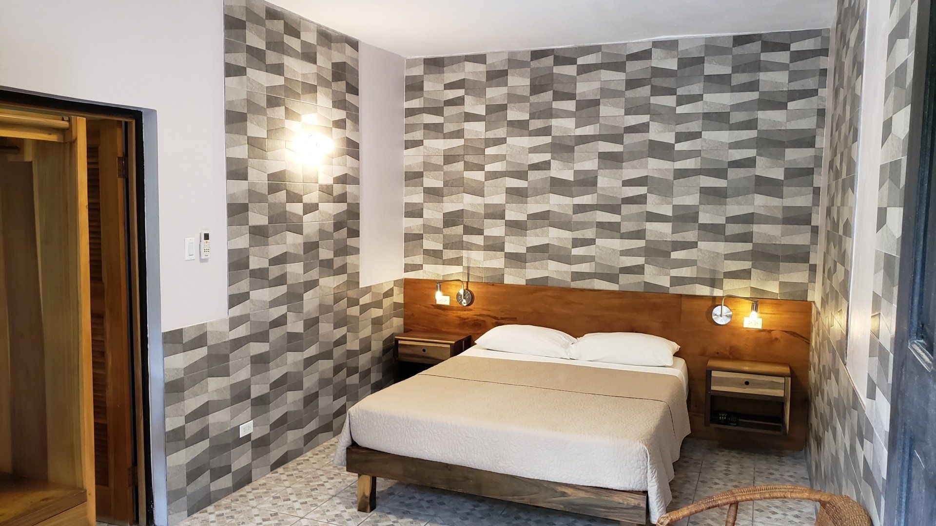 Bedroom with gray patterned wall, wooden bed frame, headboard, nightstands, and a door.