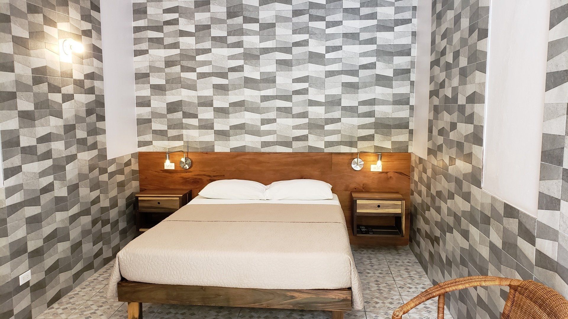 Bedroom with bed, nightstands, wood headboard, tiled walls and floor.