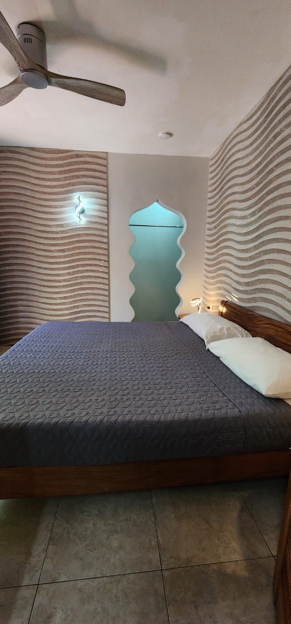 Bedroom with a bed, wavy walls, a ceiling fan, and a unique doorway.