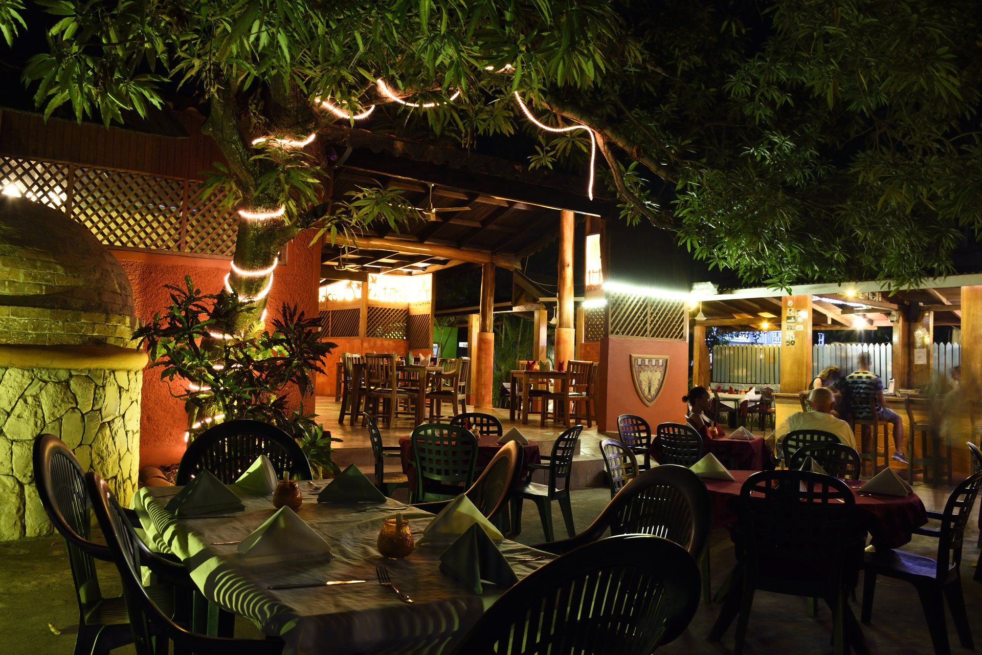 Outdoor restaurant at night with tables, chairs, and string lights.