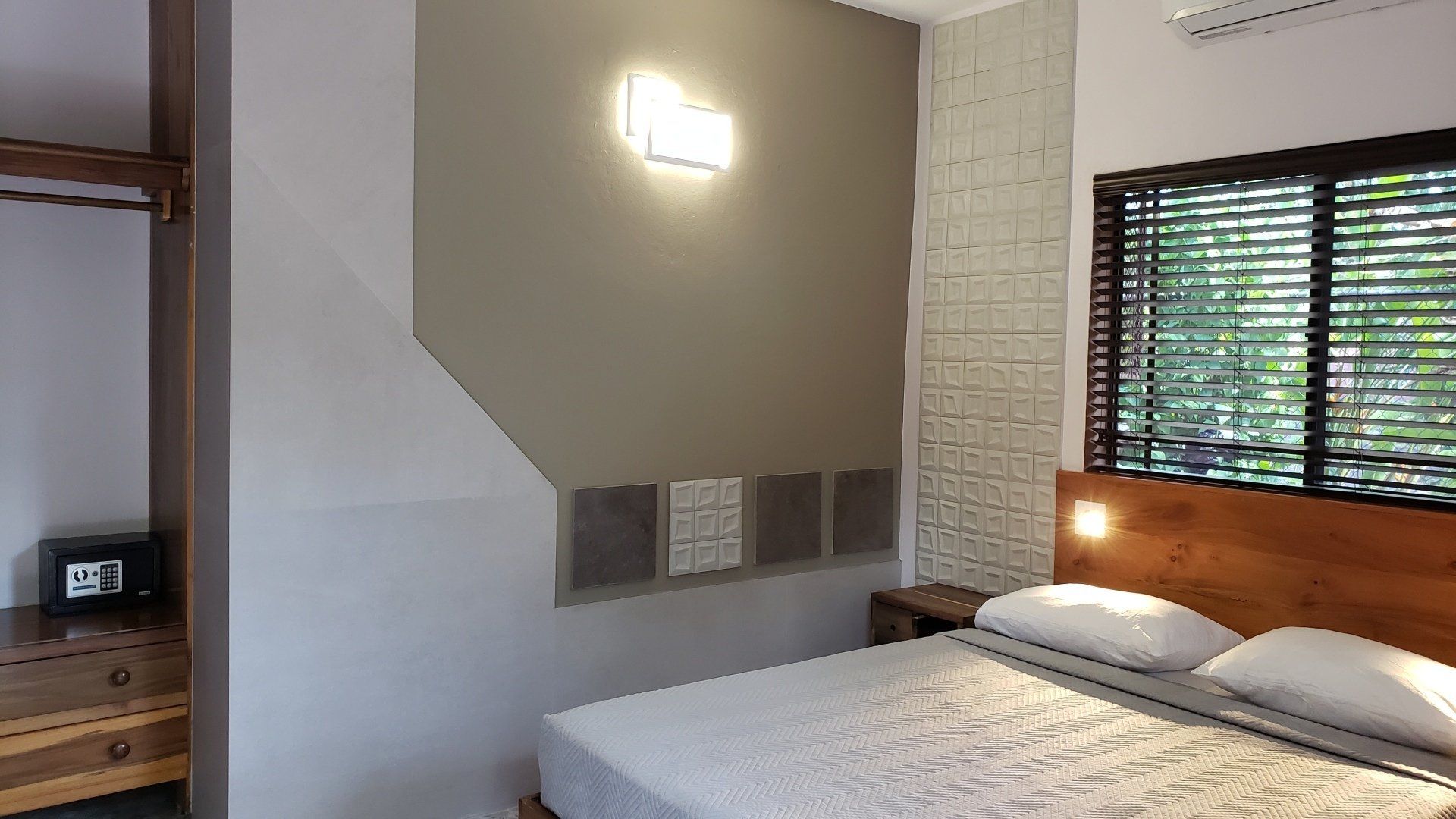 Bedroom with bed, closet, window with blinds, and decorative wall lighting.