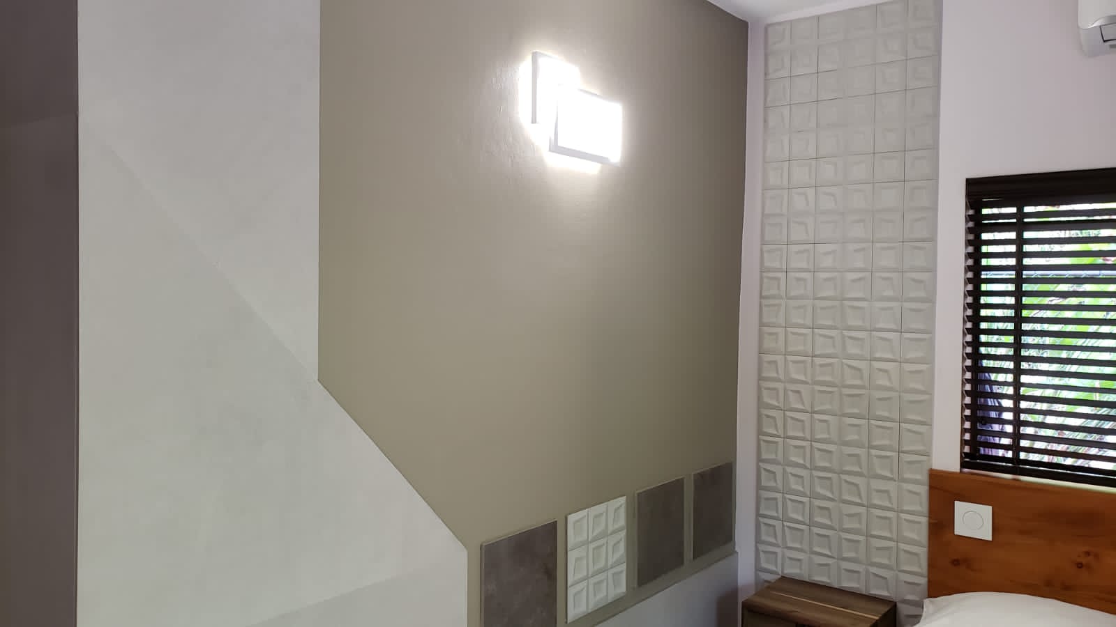 Interior of a room with light gray walls, a tiled wall, and a window with blinds.