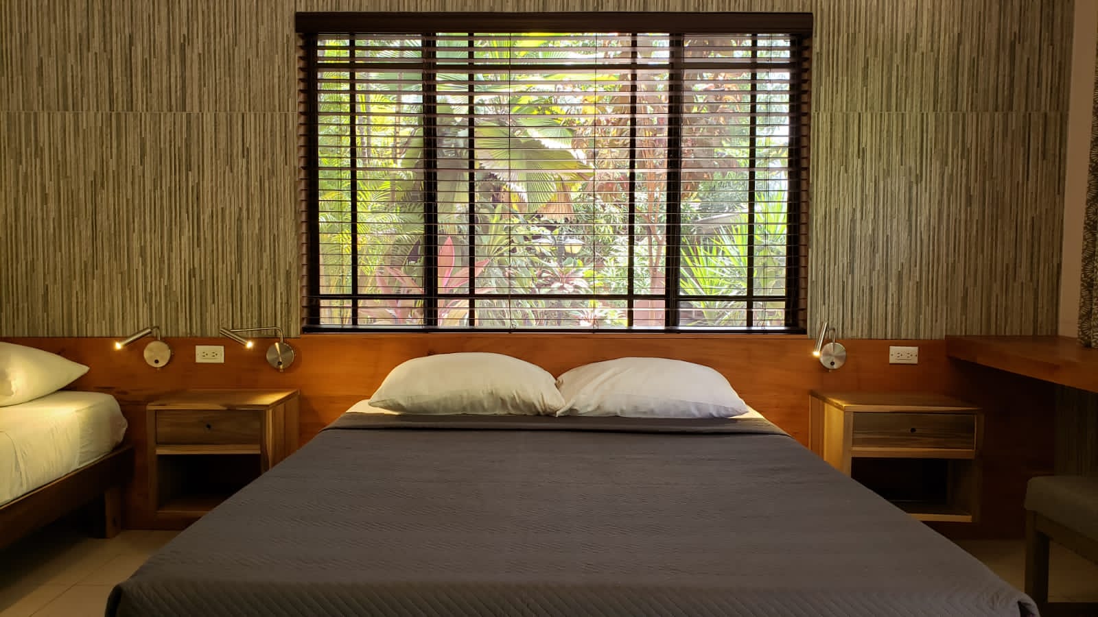 Bedroom with bed, nightstands, window with blinds, and textured wall.