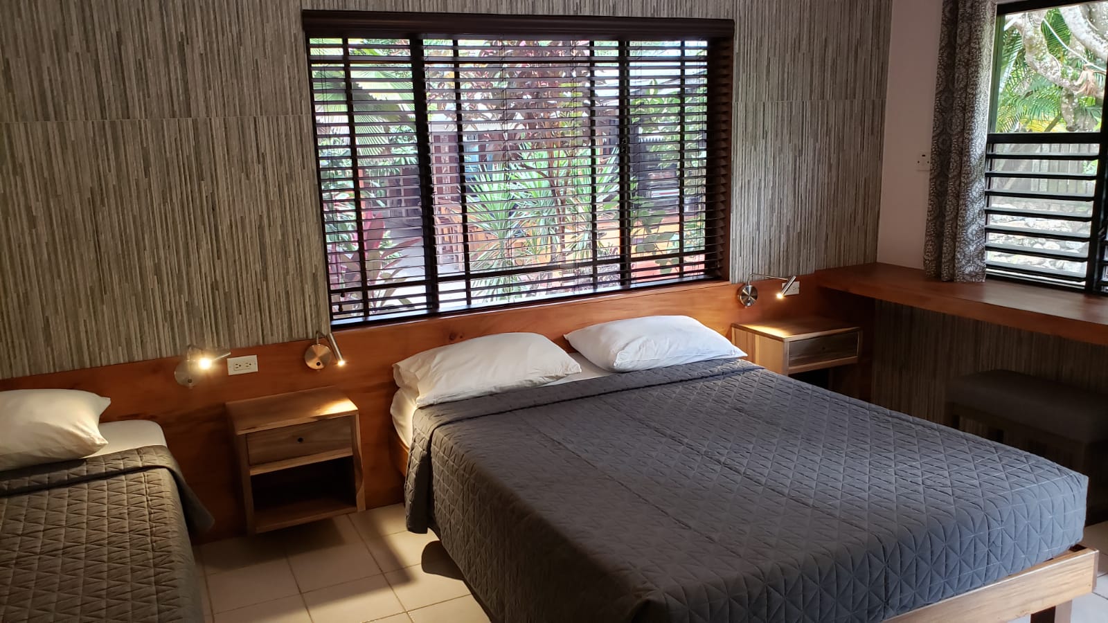 Bedroom with two beds, window, wood accents, and textured wall.