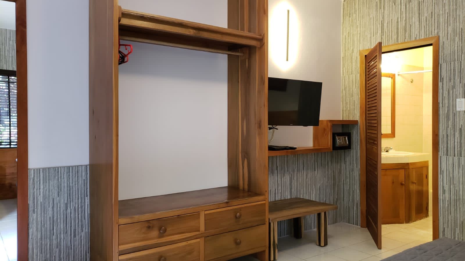 Wooden closet unit with drawers, TV, open doorway to bathroom.