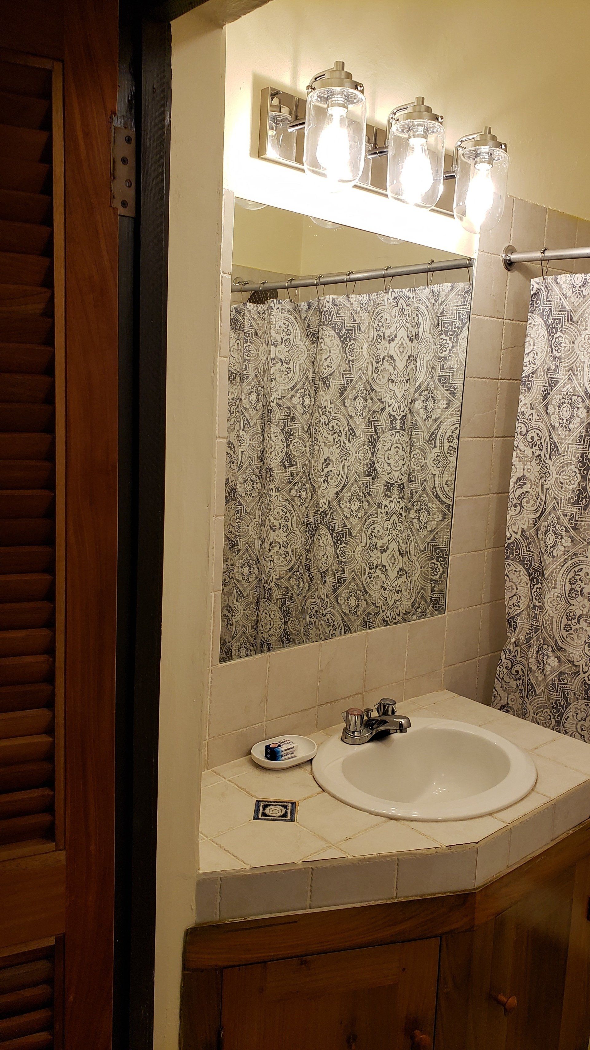 Bathroom with a white sink, mirror, and patterned shower curtain.