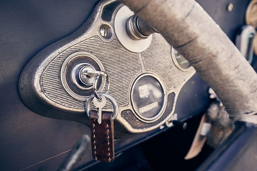 Close-up of a car ignition with keys inserted, showing a vintage dashboard detail.