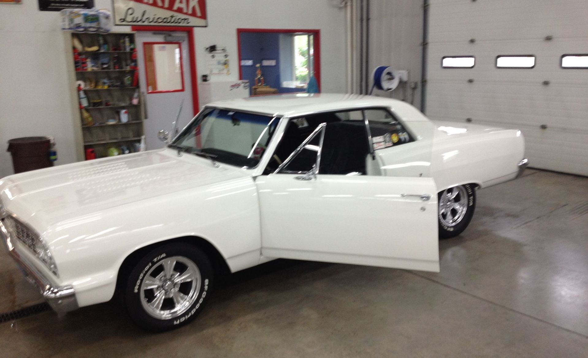 Restored white classic car inside auto body shop after full paint and restoration work