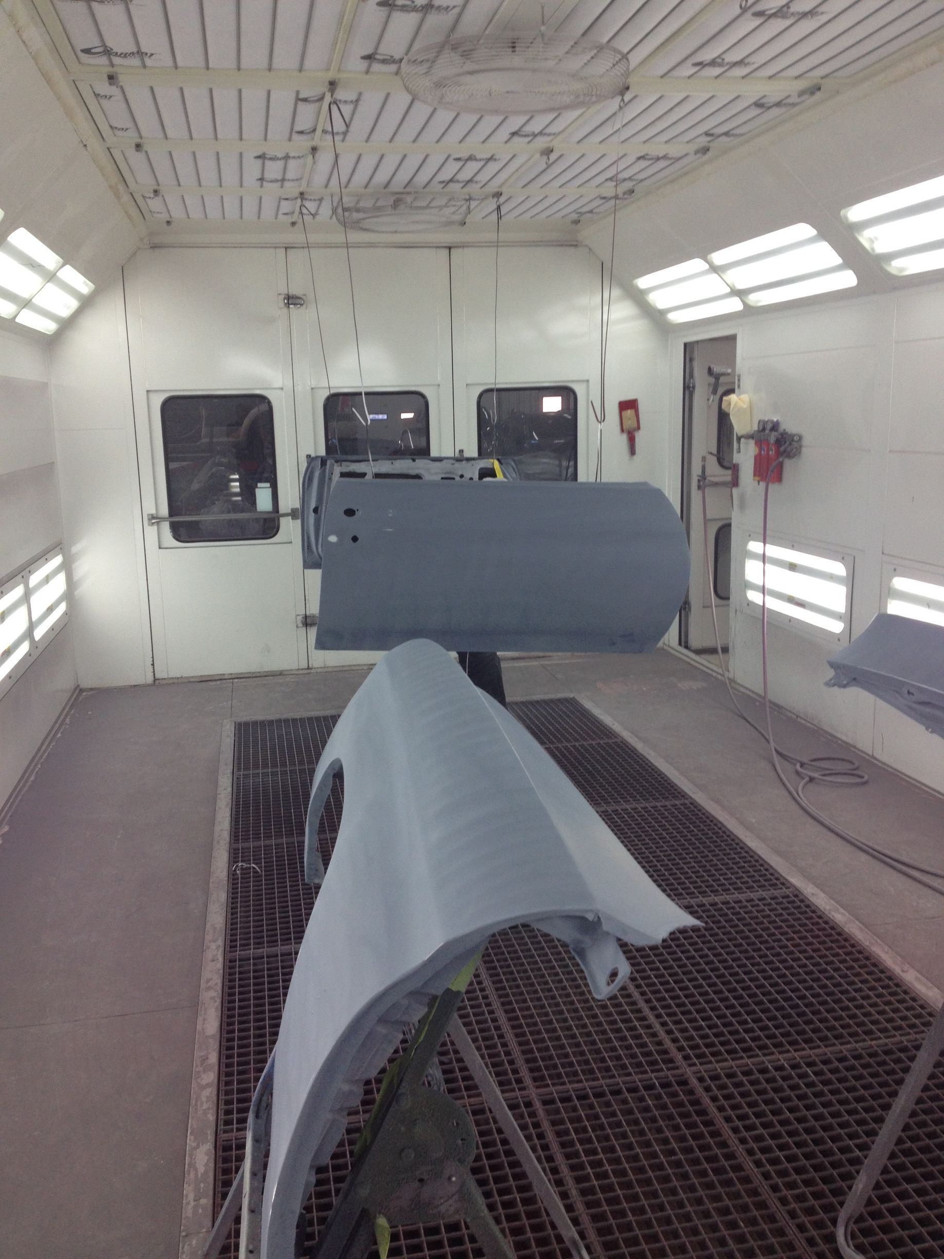 Primed car body panels in professional paint booth during auto body repair process