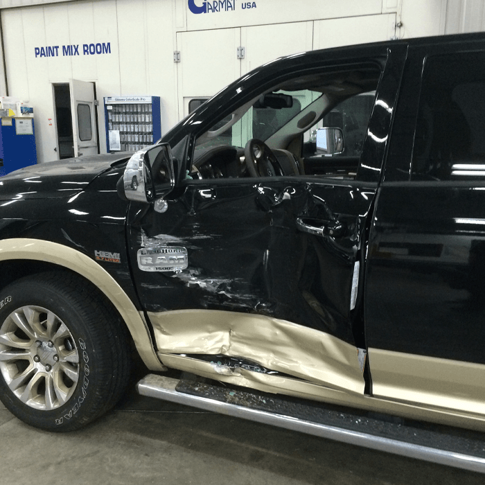 A pickup truck with a smashed driver's side door.