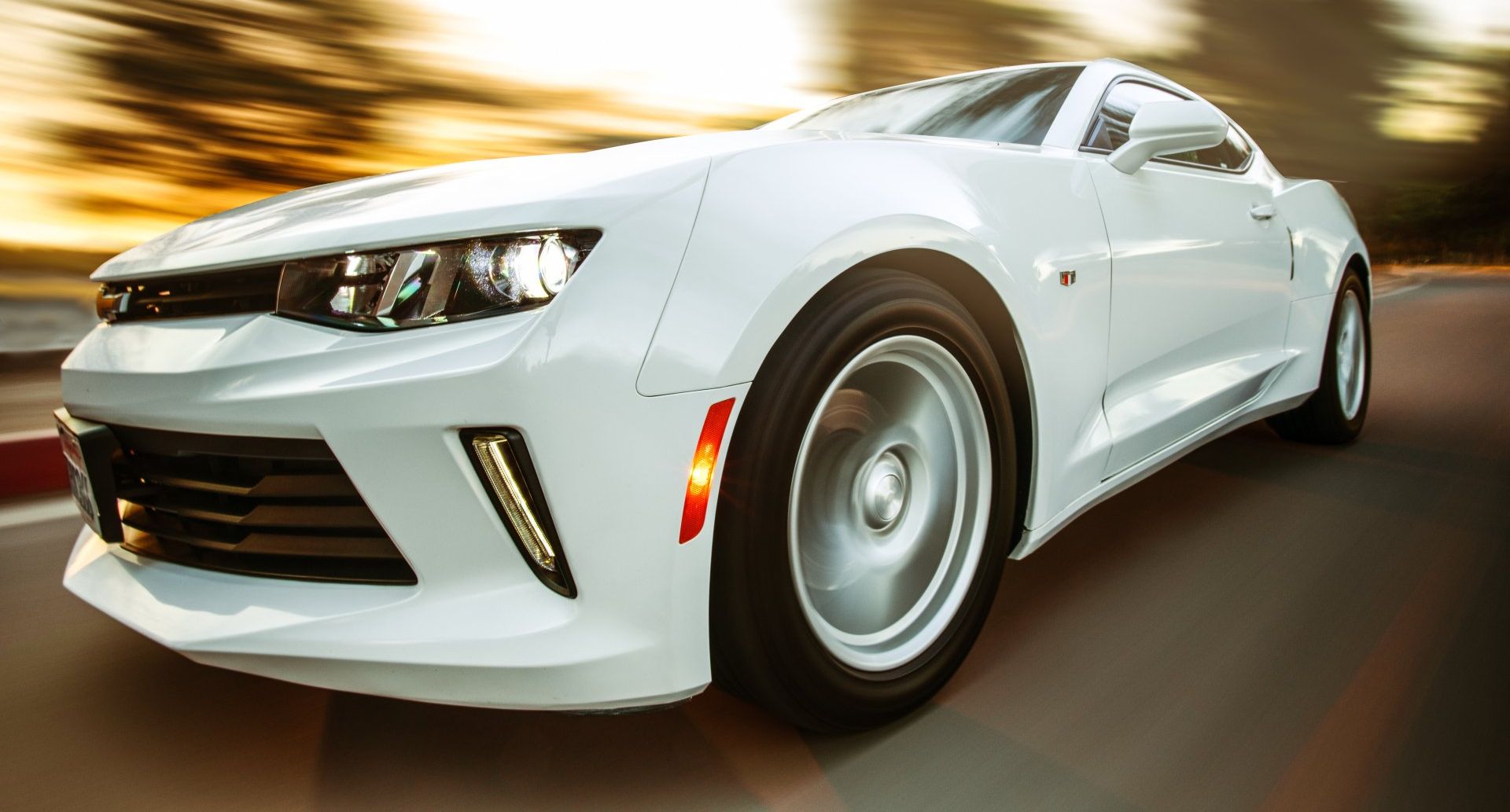 White sports car driving at high speed on a road with motion blur in the background.