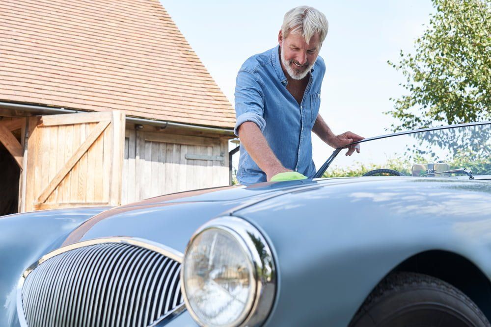 An older man cleaning his classic car.