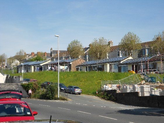 Apollo Electrical Solutions | A red car is parked on the side of the road in front of a row of houses