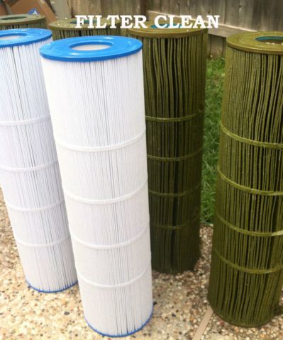 Three green and white filter cartridges are sitting on a gravel surface.