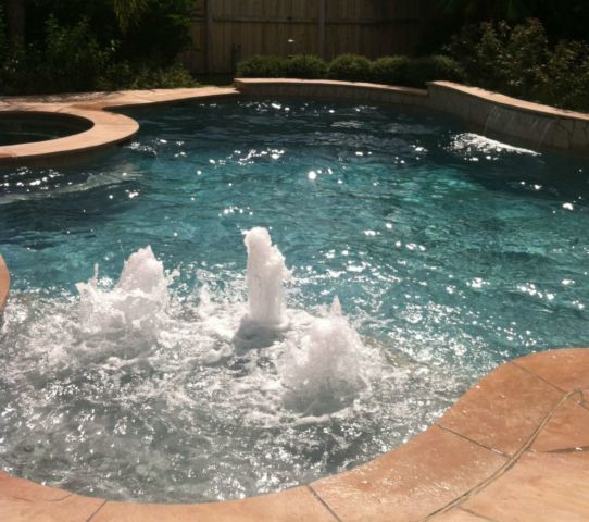 A swimming pool with a fountain in the middle of it
