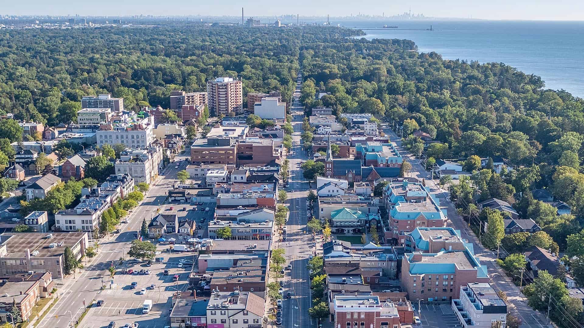 Aerial view of a dense neighborhood beside a large green park and waterfront under a clear sky