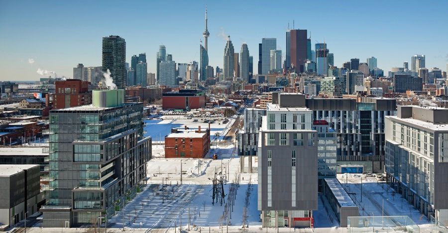 Snowy city skyline with modern buildings and a tall tower in the distance