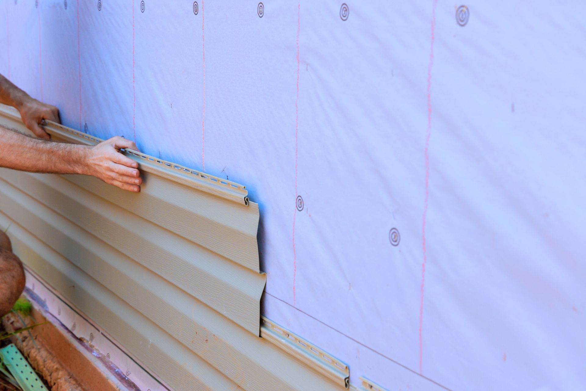 Siding installation on a house exterior with vinyl panels being installed