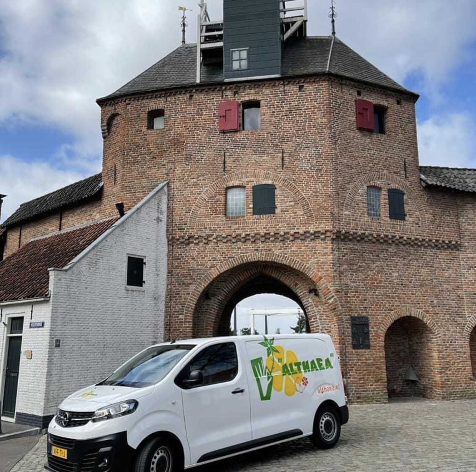 De witte Althaea bestelwagen geparkeerd voor de Vischpoort in Harderwijk
