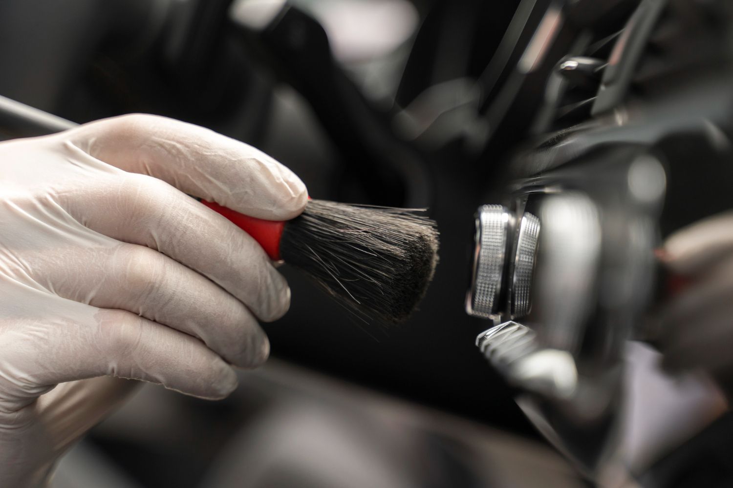 A person is cleaning a car wheel with a brush.