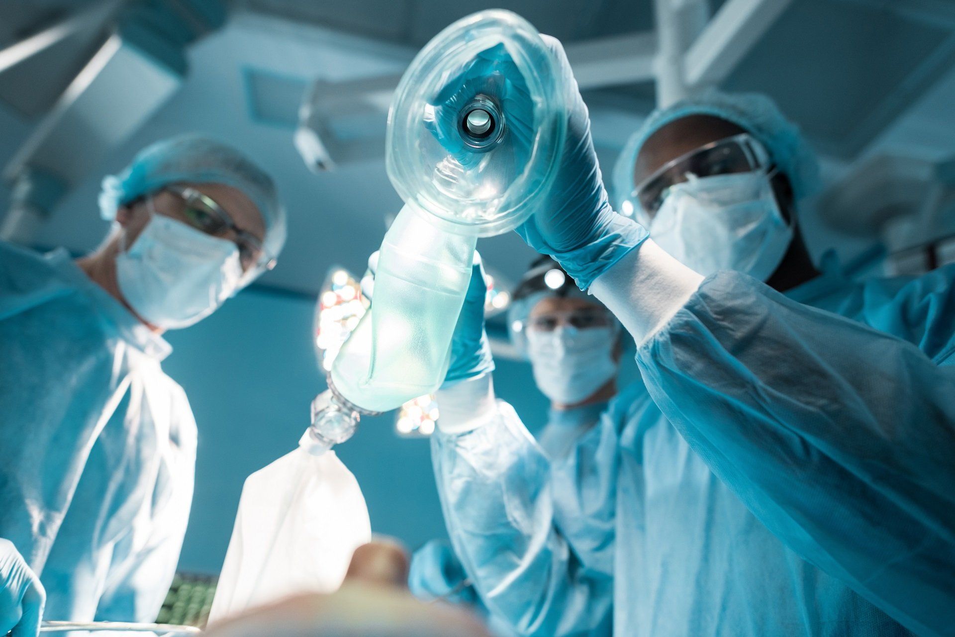 Medical team using an anesthesia mask during surgery in an operating room.