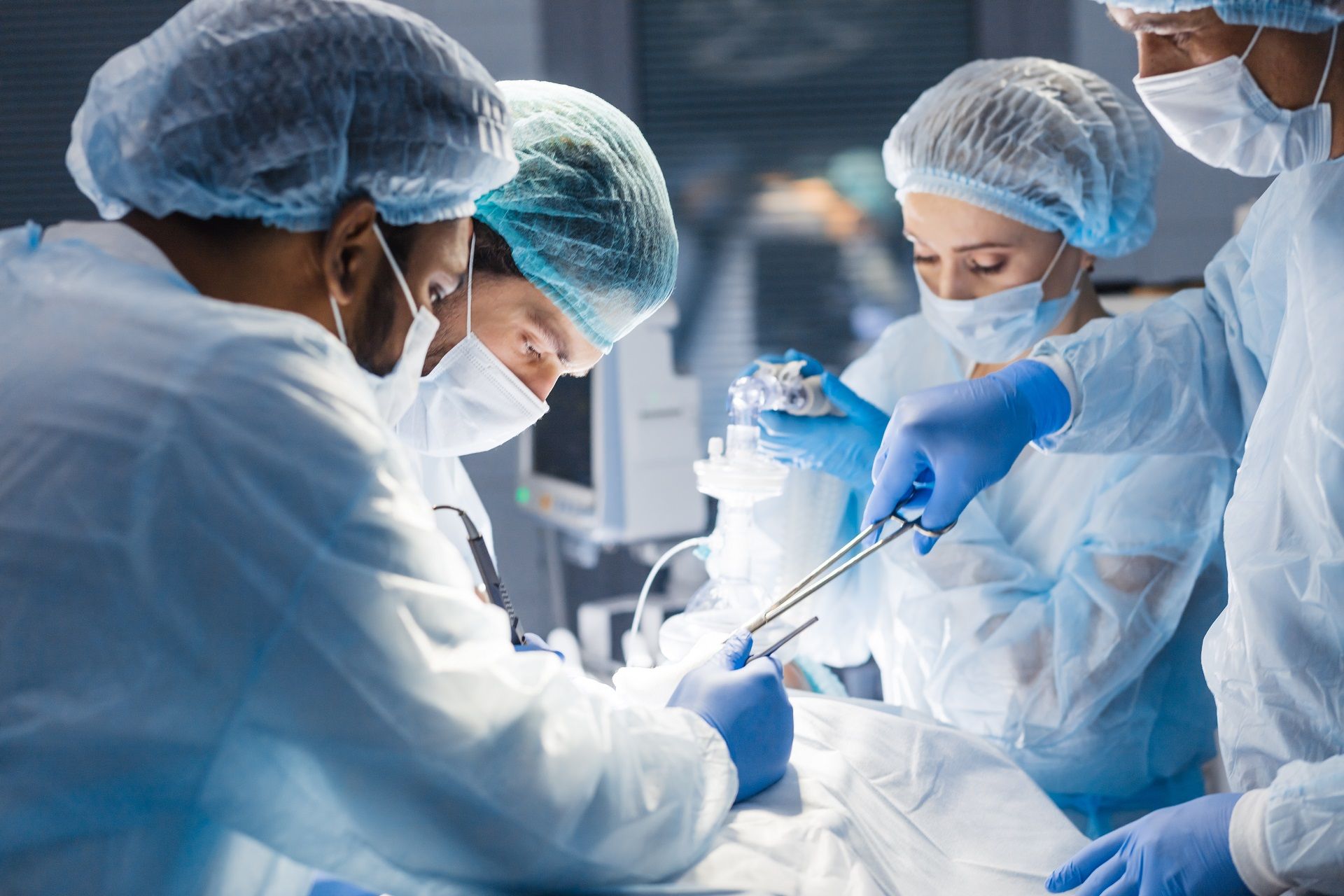 Medical team in surgical attire operating in a bright operating room.